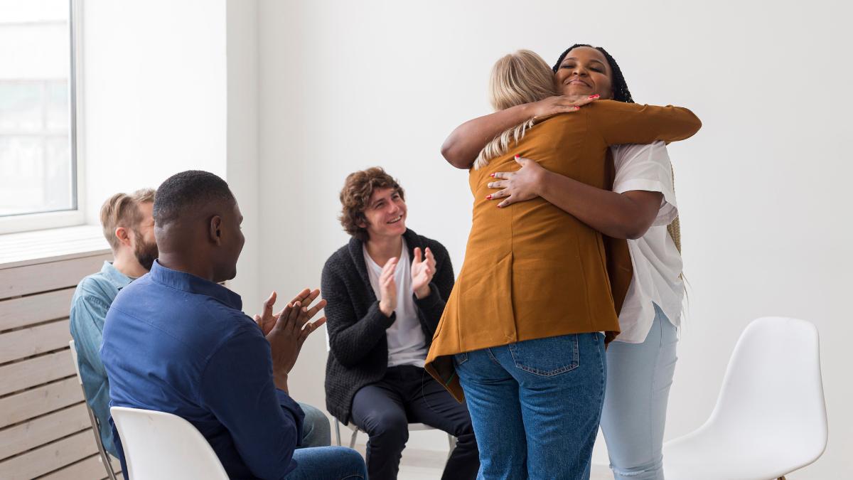 People hugging each other and celebrating milestones during recovery, an essential aspect of how to help someone with addiction.